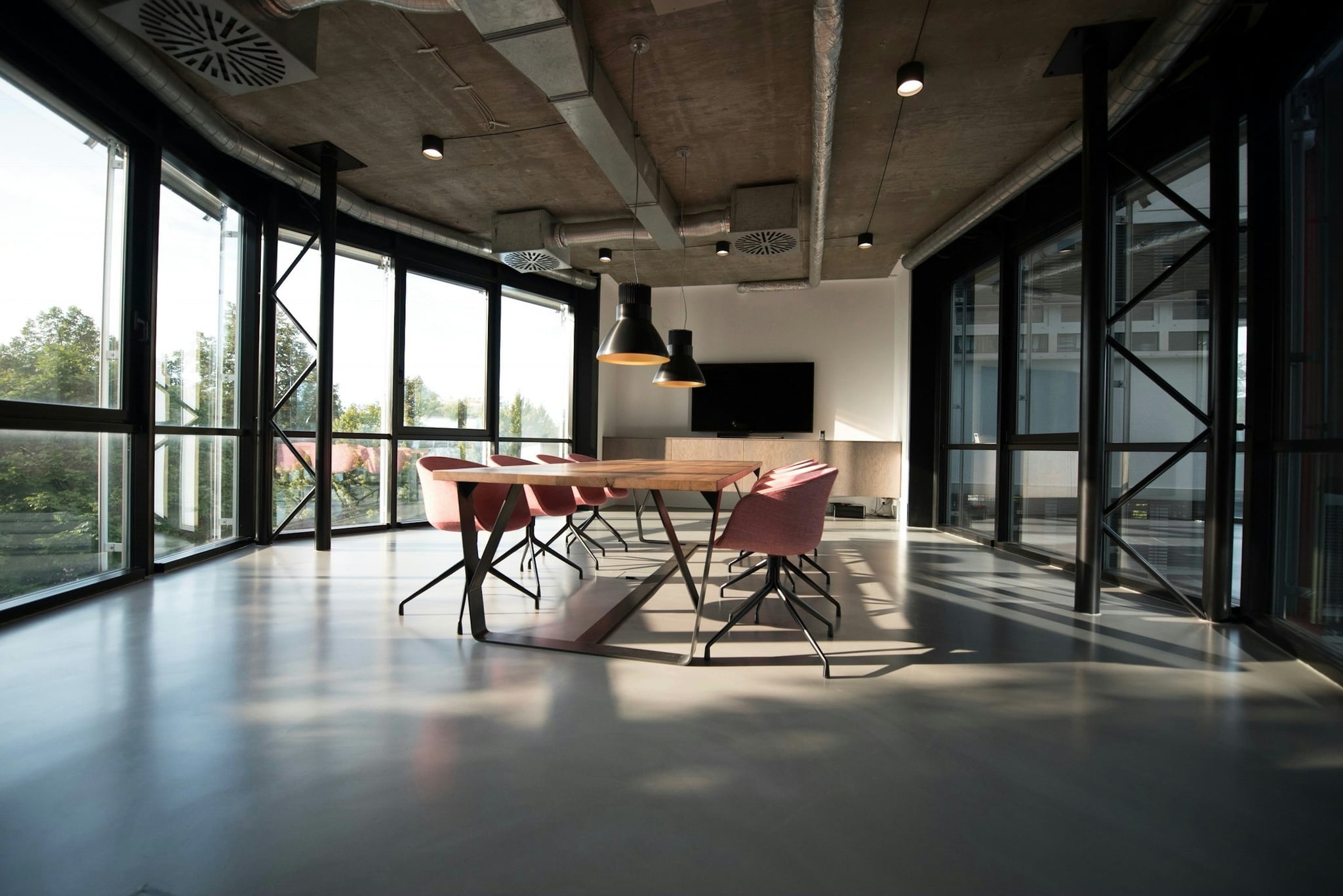 Sunlit, modern studio workspace with a long table and quiet industrial details