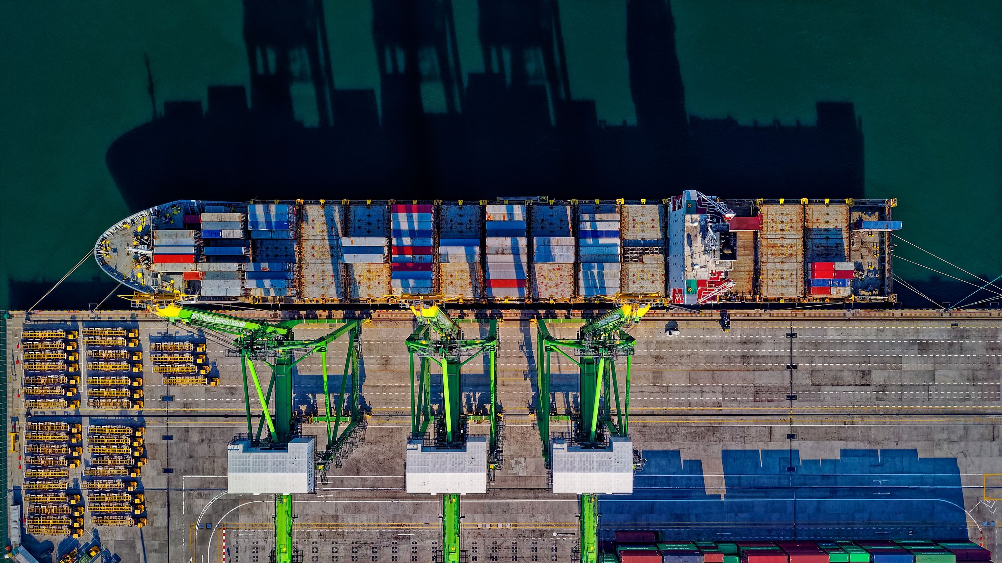 A cargo ship being serviced by cranes in a global container port