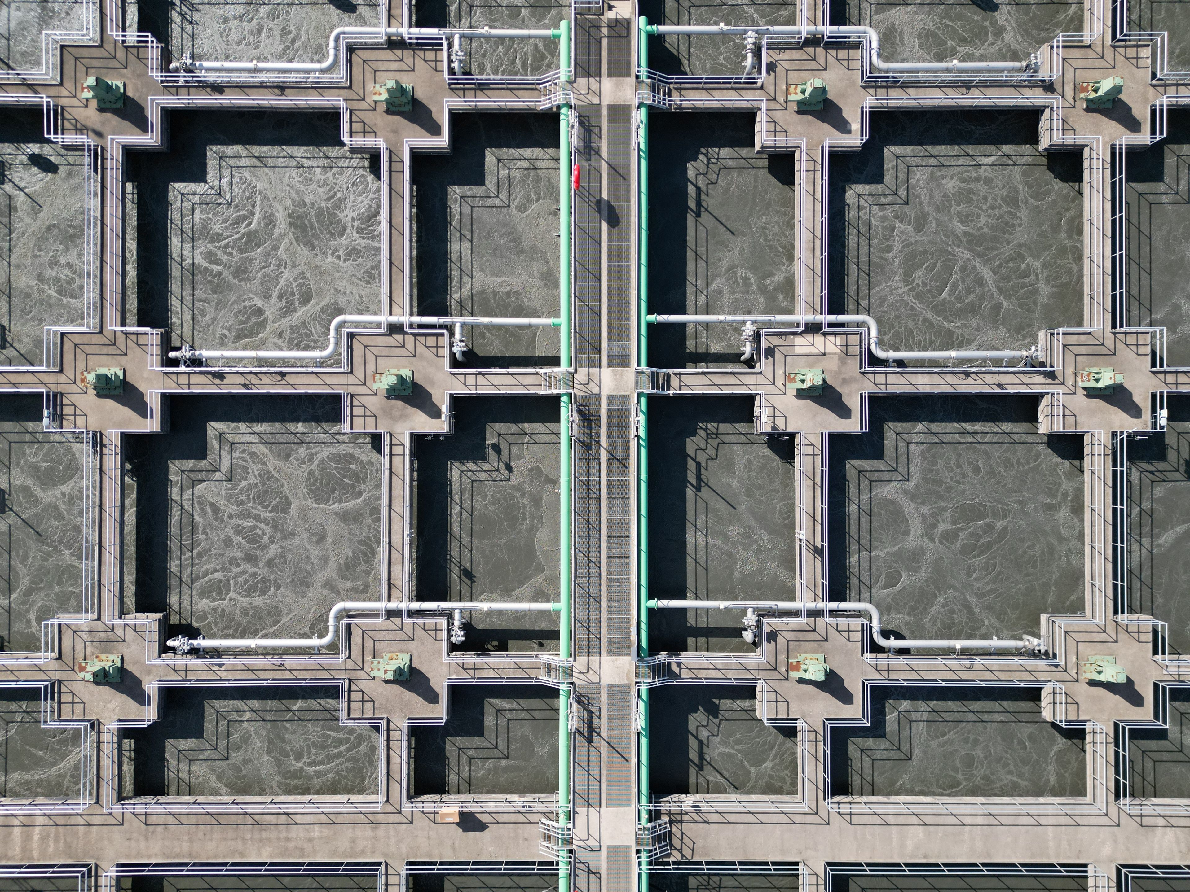 Aerial view of a municipal water treatment facility with aeration tanks, pipes, and a central service spine